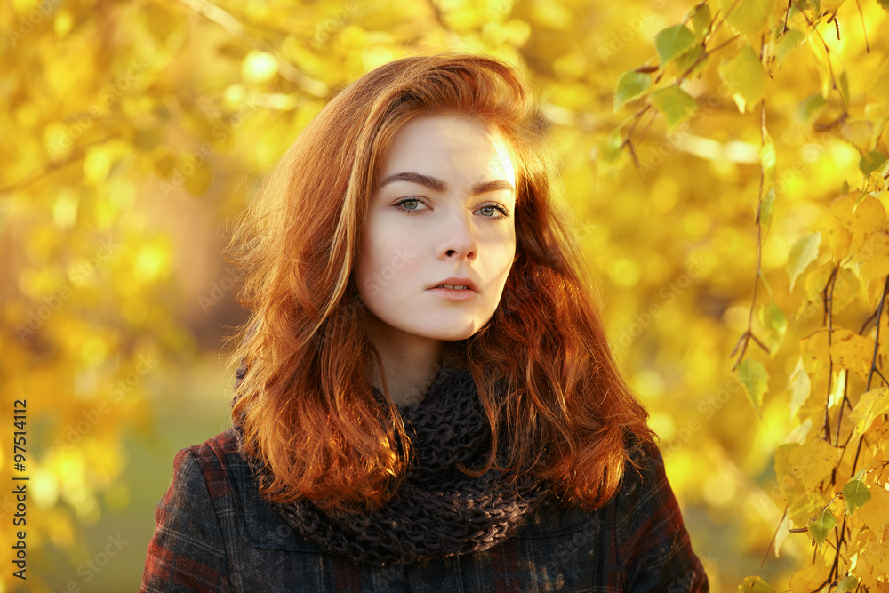 Outdoors portrait of young beautiful redhead woman in scarf and jacket on yellow autumn foliage background Outdoors portrait of young beautiful redhead woman in scarf and jacket on yellow autumn foliage background