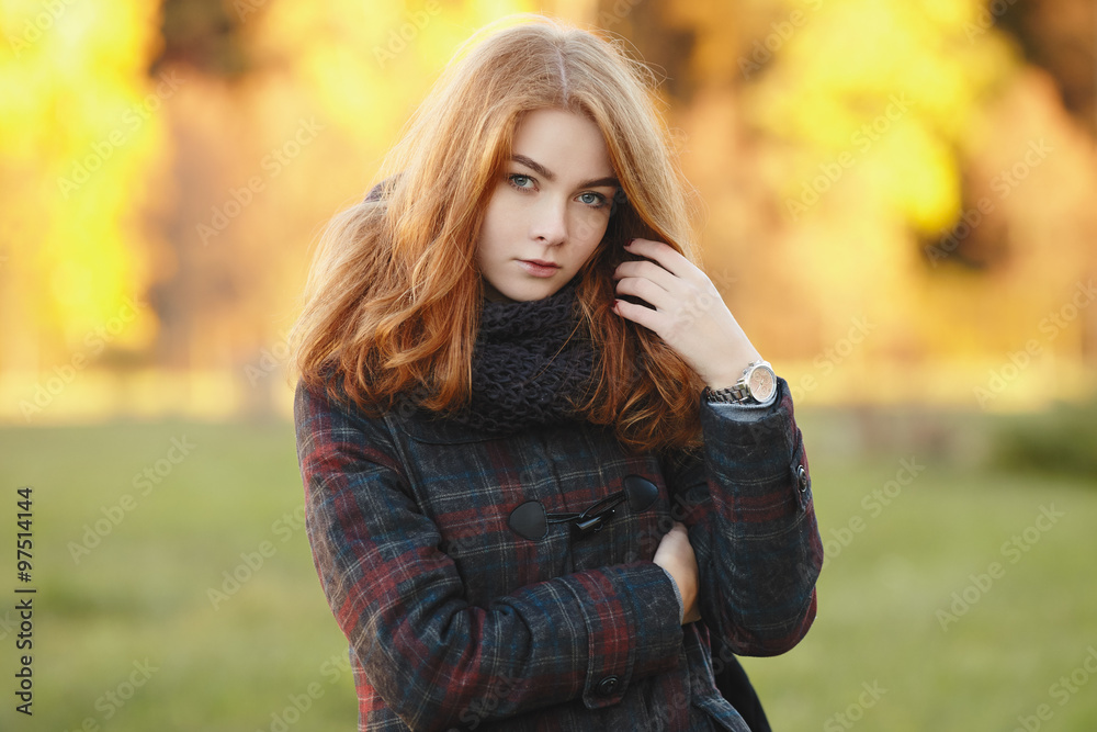 Outdoors portrait of young beautiful redhead woman in scarf and jacket on yellow autumn foliage background Outdoors portrait of young beautiful redhead woman in scarf and jacket on yellow autumn foliage background