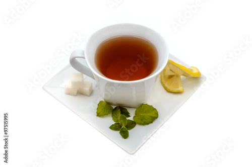 A cup of tea with sugar cubes, lemon and mint on a saucer