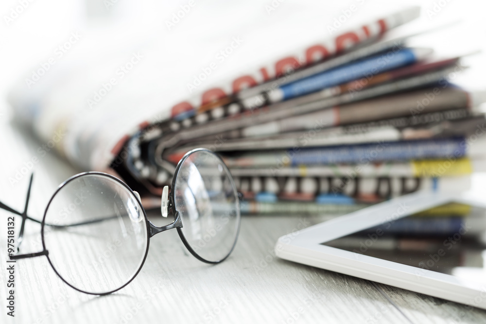 Stack of newspapers, eyeglasses and digital tablet Stack of newspapers, eyeglasses and digital tablet