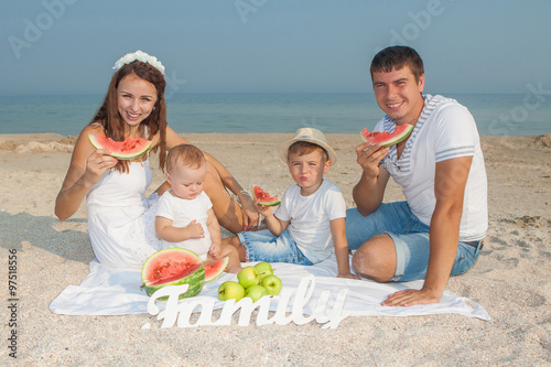 Family with watermelon on the beach