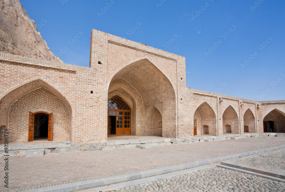 Ancient caravanserai in the mountains under clear blue sky in Iran