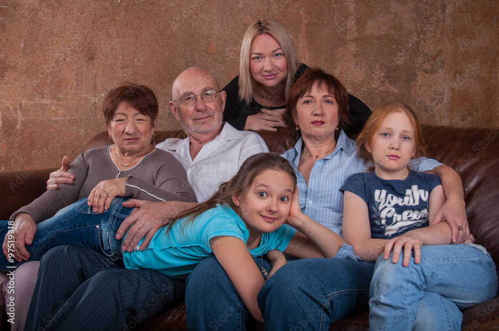 Большая семья с бабушкой дедушкой, мамой и ребенком сидят на диване