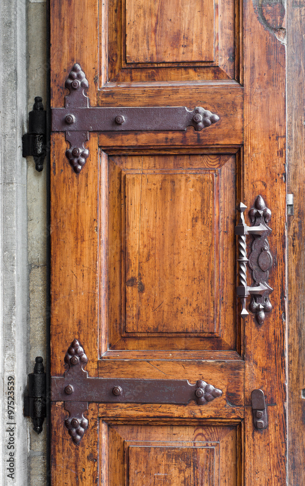 Obraz premium Old wooden door with decorative hinge forged in steel