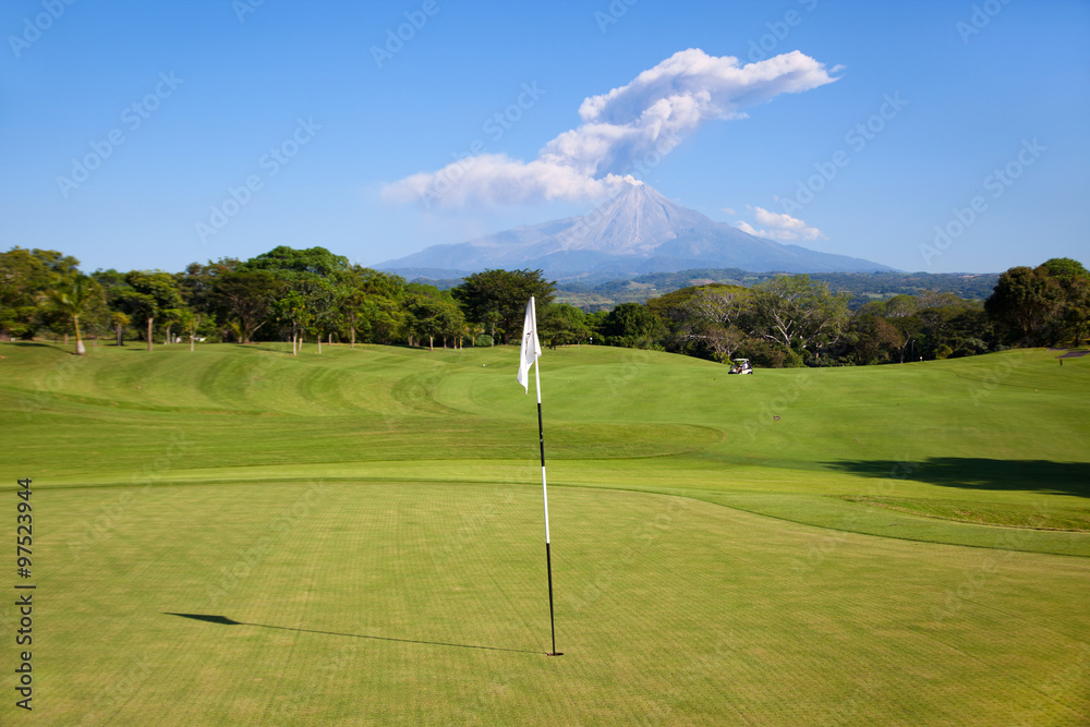 Obraz premium On the green with an active volcano in the background