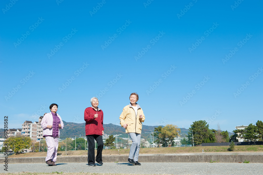 青空を背景に歩いている3人のアジア人高齢者