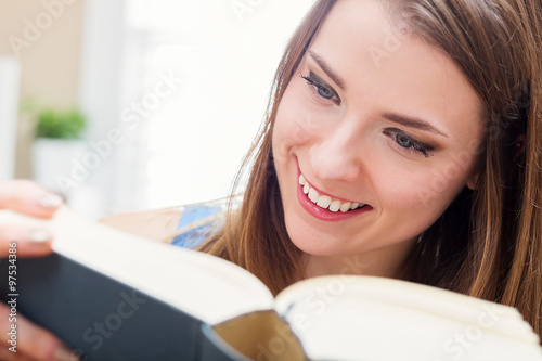 Happy young woman reading a book