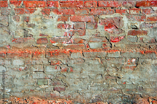 Red brick wall half covered with cement
