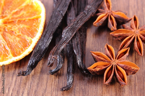 Star anise, fragrant vanilla and dried orange on wooden surface