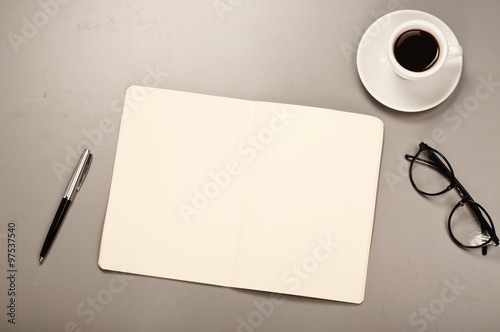 Open notebook with blank pages with a pen, glasses, coffee