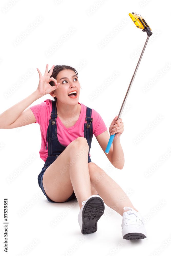 Young woman taking picture with smartphone selfie stick Young woman taking picture with smartphone selfie stick