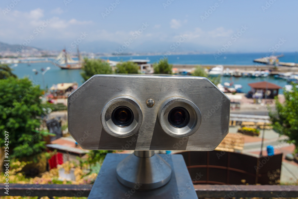 Sighting place with a view of the sea port. Binocular close-up in the foreground.