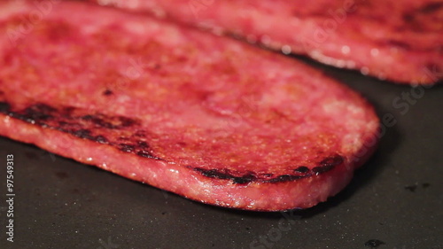 HD macro footage of a slice of canned meat product being fried in a pan photo