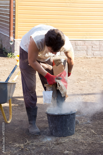 man pours a bag of cement in bucket