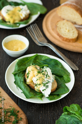Poached egg on a piece of bread with spinach on the wooden table