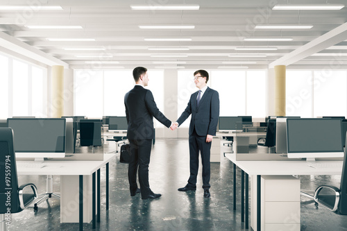 Businessmen shake hands ini modern open space office © Who is Danny