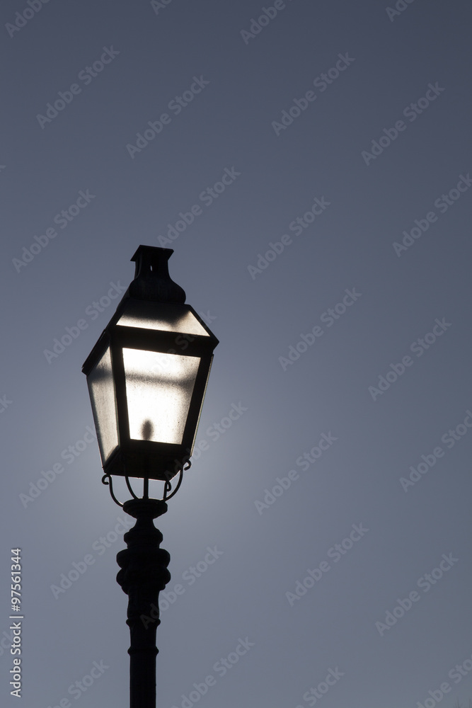 Old street lamp on a background of dramatic dark blue skyBacklight. Highlights sun. Space for text