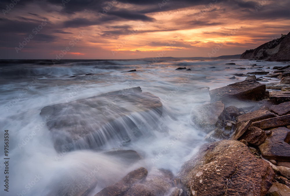Stormy sea. Amazing sea sunrise with slow shutter and waves flowing out.
