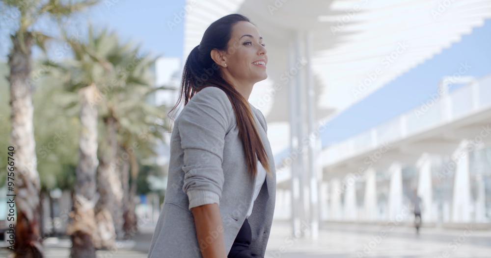 Fototapeta premium Elegant woman sitting on a bench on a promenade