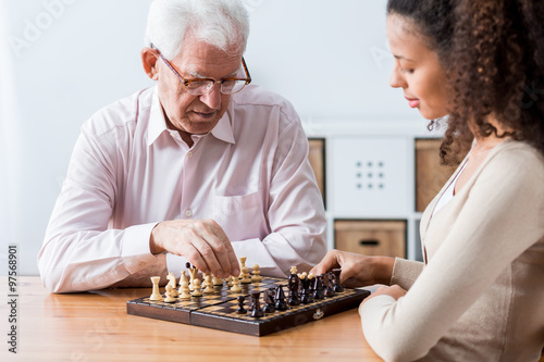 Retiree and caregiver playing chess