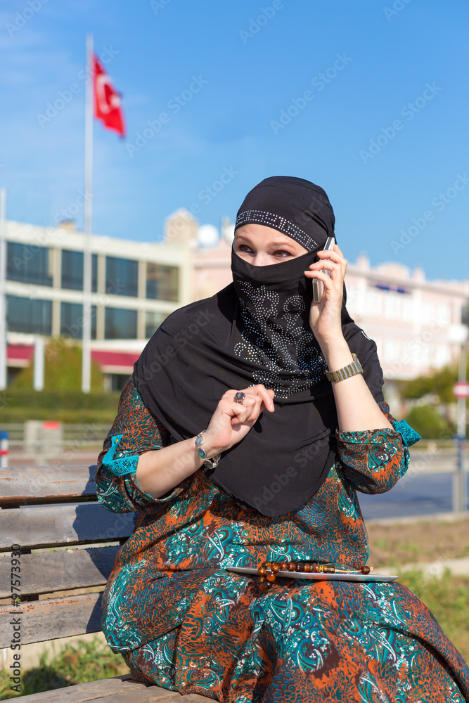 Obraz premium Lady in Black Hijab Holding Telephone and talking