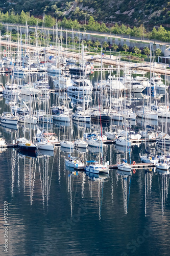 Accumulation of yachts on the water against the sky,  mountains and a small village © watman