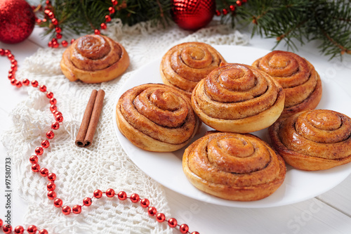 Cinnamon bun rolls homemade christmas sweet dessert on white vintage table with new year decorations. Traditional swedish kanelbullar baked pastry photo