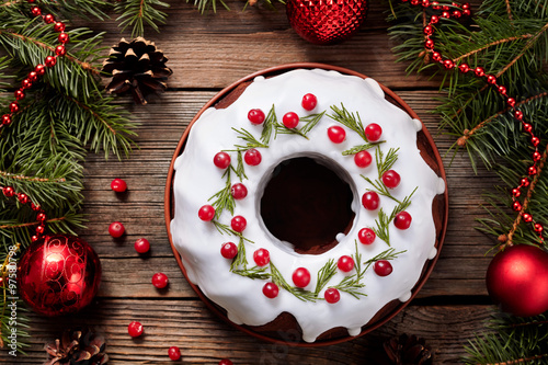 Traditional homemade christmas cake holiday dessert with cranberry in new year tree decorations frame on vintage wooden table background. Rustic style