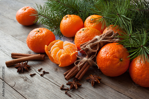  Tangerines with cinnamon, anise and fir branches on a wooden table. Christmas background card with fruits.