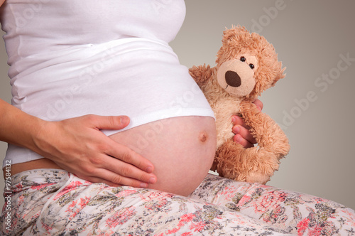 Pregnant woman with a toy bear in hands