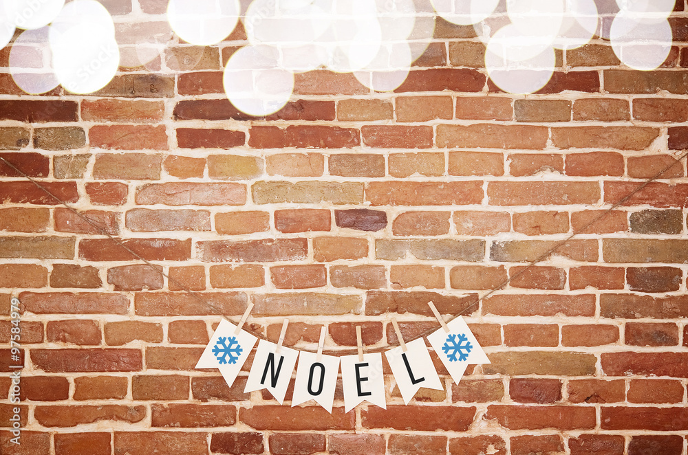 Black and white NOEL and blue snowflake paper card homemade flag garland with top blurred lights border decoration on rustic brick wall background. Horizontal postcard with space for text or lettering Black and white NOEL and blue snowflake paper card homemade flag garland with top blurred lights border decoration on rustic brick wall background. Horizontal postcard with space for text or lettering