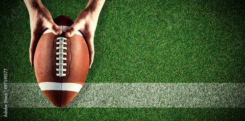 Composite image of american football player holding up football