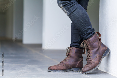 Young fashion man's legs in jeans and brown boots on the floor