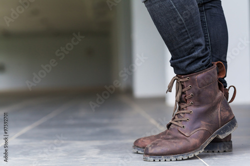 Young fashion man's legs in jeans and brown boots on the floor