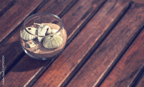 Shells in a glass jar on a wooden beach with vintage color effect