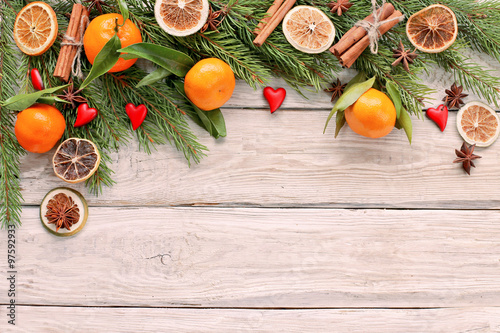 Christmas tree branch with mandarin , cinnamon, hearts on wooden background 