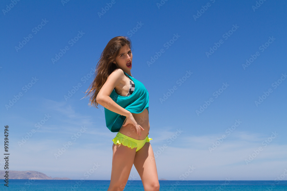 Brunette cheerful teenage in beachwear enjoys the summer.