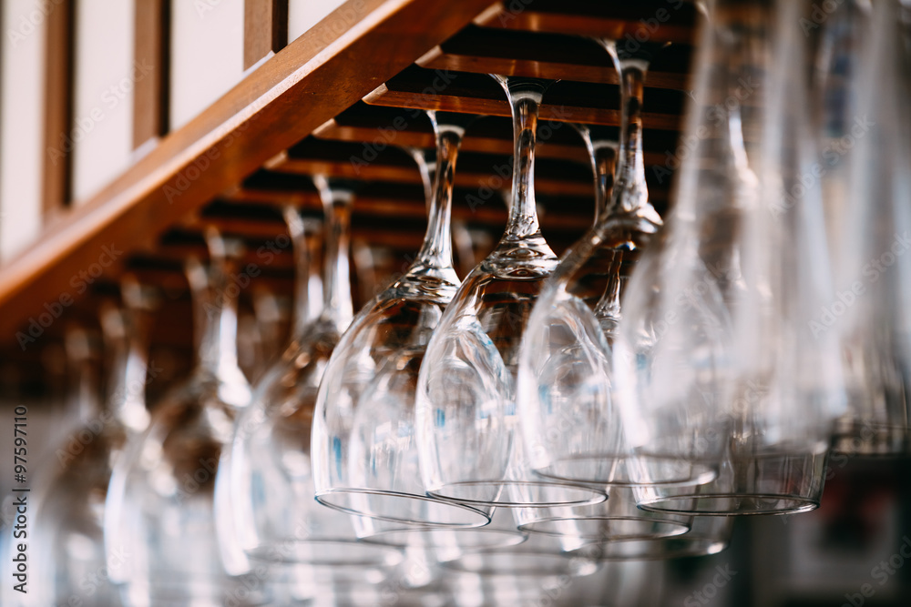 Empty glasses for wine above a bar rack. Hanging wine glasses in Empty glasses for wine above a bar rack. Hanging wine glasses in