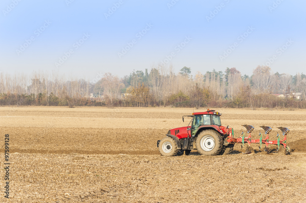 Obraz premium Red Tractor Plowing in Autumn.