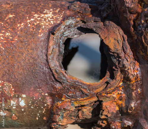 Close up of a rusty metal industrial pipe with rusted through hole