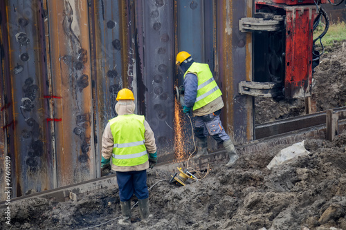 Worker with protective equipment grinding steel beams