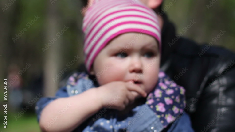father kissing her child who chews his finger father kissing her child who chews his finger