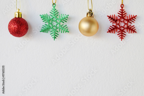 Snow flake and ball ornaments hanging on white wall background
