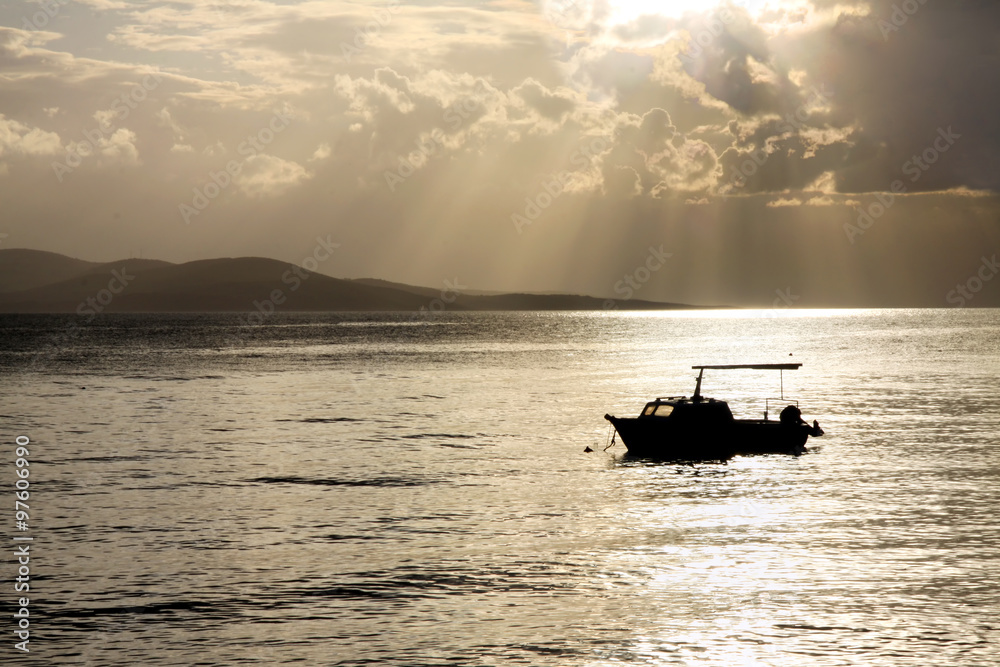 Sun shining through clouds on a fishing boat in Makarska, Croatia.