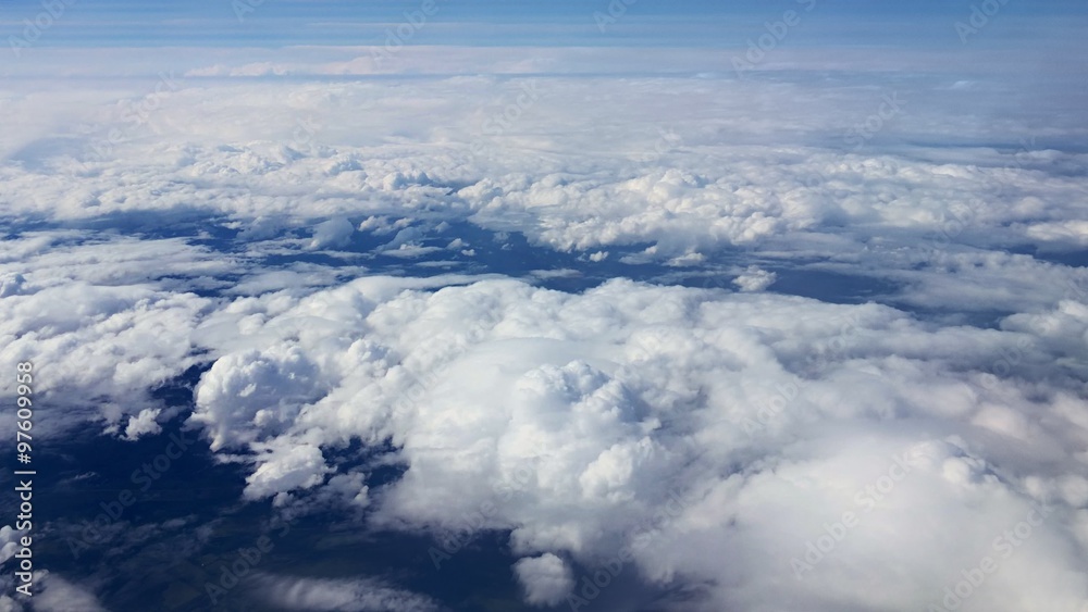 Traveling by air. View through an airplane window. Flying over the Mediterranean Sea through cirrus and cumulus clouds and little turbulence, showing Earth's atmosphere. Traveling by air. View through an airplane window. Flying over the Mediterranean Sea through cirrus and cumulus clouds and little turbulence, showing Earth's atmosphere.