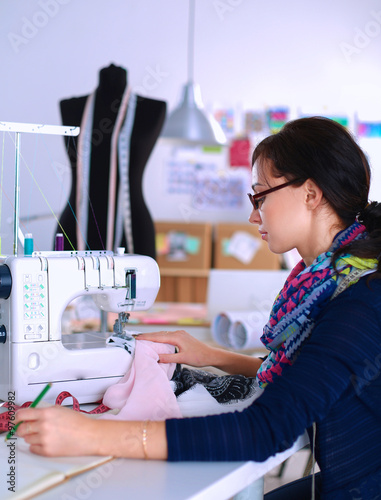 Young woman sewing while sitting at her working place