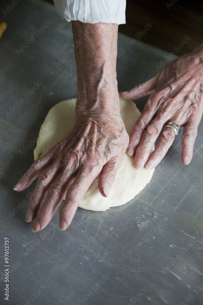 Fototapeta premium close up of an elderly woman's hands making a pie in the kitchen