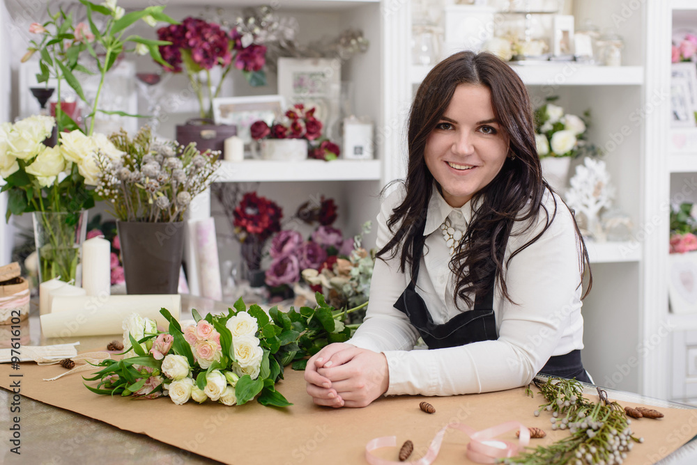 Portrait of smiling florist standing near the table with flowers Portrait of smiling florist standing near the table with flowers