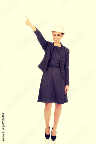 Businesswoman in hard hat pointing up.