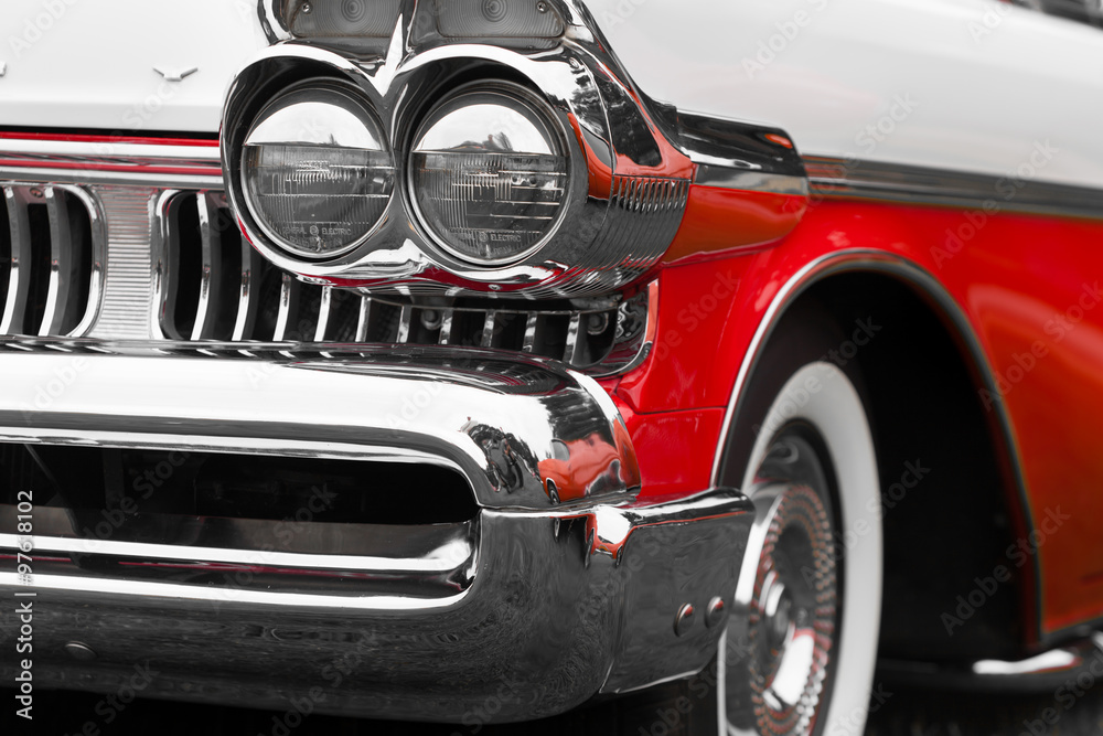Close-up of right headlights of a red and white shiny classic vintage car